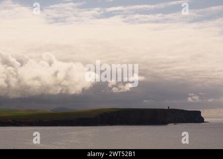 Blick von Brough of Birsay zum Kitchener Memorial am Marwick Head an der Westküste von Festland Orkney mit Wolkenbildung darüber Stockfoto