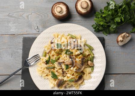 Vegetarische Pasta mit Pilzen, Petersilie, Bohnen und Käse auf grauem Holztisch, Blick von oben Stockfoto