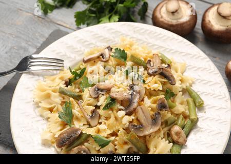 Vegetarische Pasta mit Pilzen, Petersilie, Bohnen und Käse auf grauem Holztisch, Nahaufnahme Stockfoto