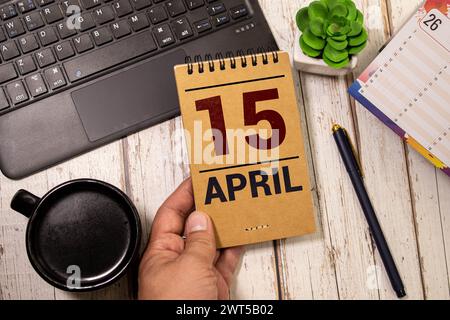 April. Tag 15 des Monats, Kalender auf Holztisch und türkisfarbenem Hintergrund. Frühlingszeit, Leerraum für Text Stockfoto