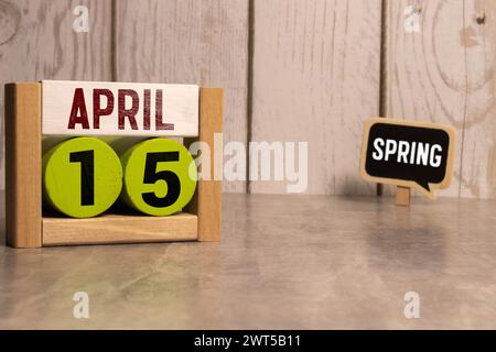 April. Tag 15 des Monats, Kalender auf Holztisch und türkisfarbenem Hintergrund. Frühlingszeit, Leerraum für Text Stockfoto