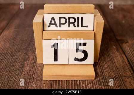 April. Tag 15 des Monats, Kalender auf Holztisch und türkisfarbenem Hintergrund. Frühlingszeit, Leerraum für Text Stockfoto