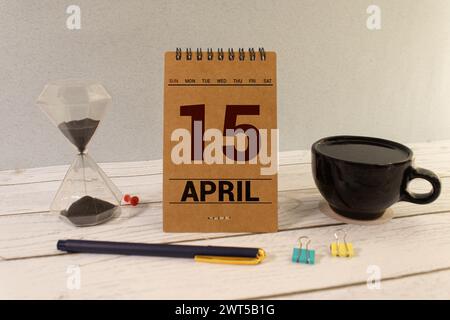 April. Tag 15 des Monats, Kalender auf Holztisch und türkisfarbenem Hintergrund. Frühlingszeit, Leerraum für Text Stockfoto