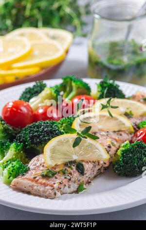 Lachssteak mit Gemüse, gebackenes Lachsfilet mit Brokkoli und Tomaten auf einem Teller, vertikal Stockfoto