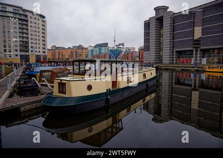 Ein Kanalkahn, der auf immer noch schwarzem Wasser mit dem Imperial war Museum North im Hintergrund am Leeds Dock in Leeds, West Yorkshire, England, verankert ist. Stockfoto