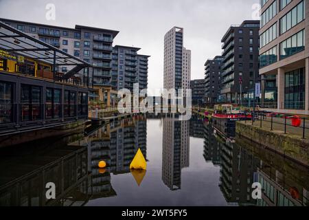 Moody Grey Sky über dem Leeds Dock, mit Reflexionen von Gebäuden im immer noch dunklen Wasser, Leeds, West Yorkshire, England. Stockfoto