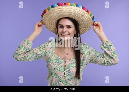 Junge Frau mit mexikanischem Sombrero-Hut auf violettem Hintergrund Stockfoto