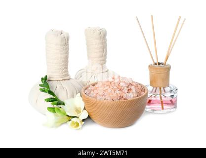 Spa-Zusammensetzung. Kräutermassagebeutel, Meersalz, Schilflufterfrischer und schöne Blumen auf weißem Hintergrund Stockfoto