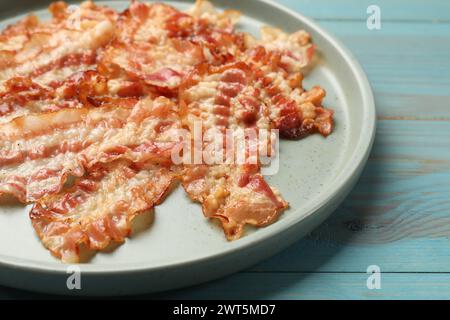 Köstliche gebratene Speckscheiben auf blauem Holztisch, Nahaufnahme Stockfoto