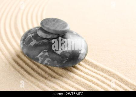 Zen-Gartensteine auf beigem Sand mit Muster. Leerzeichen für Text Stockfoto