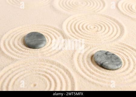 Zen-Gartensteine auf beigem Sand mit Muster Stockfoto