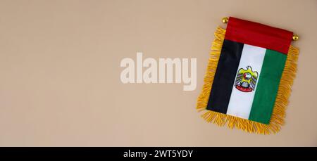 Nationales Symbol der VAE. Kleine Flagge der Vereinigten Arabischen Emirate mit Wanderfalke auf neutralem beigem Hintergrund. Kopieren Sie den Platz für Ihren Text. Das Konzept der Unabhängigkeit des Nationaltages Stockfoto