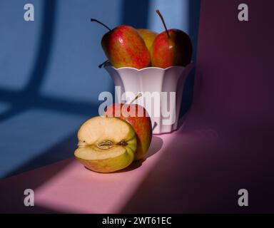 Foto eines Apfels in einem Behälter auf einem rosa und blauen Hintergrund Stockfoto