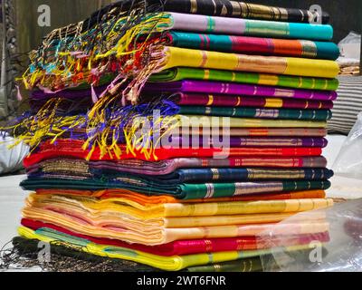 Ordentlich gestapelte farbenfrohe Designer-Seidensaris in Regalen in einem Textilgeschäft. Unglaubliches Indien. Stockfoto
