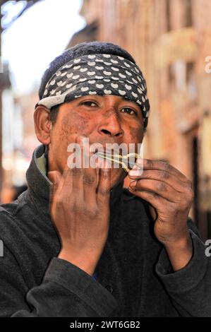 Ein Mann spielt auf der Straße die Harfe des juden, gekleidet in einem schwarz-weißen Schal, Kathmandu Valley. Kathmandu, Nepal Stockfoto