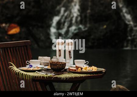 Ein Frühstück bestehend aus tropischen Früchten, Acai-Schüssel, Crepes und Toast mit Tee und Kaffee, an einem Flussufer Stockfoto