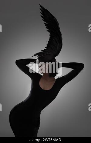 Vogel-, Mode- und Kunststil-Frau in einem Studio mit Kopfstück, Federhut und abstraktem Design mit einzigartiger Kreativität. Krähe, Silhouette und Schatten mit Stockfoto