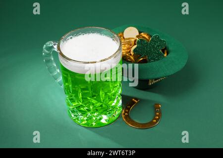 St. Patrick's Day Party. Grünes Bier, Leprechaun Hut mit Gold, Hufeisen und dekorativem Kleeblatt auf grünem Hintergrund Stockfoto