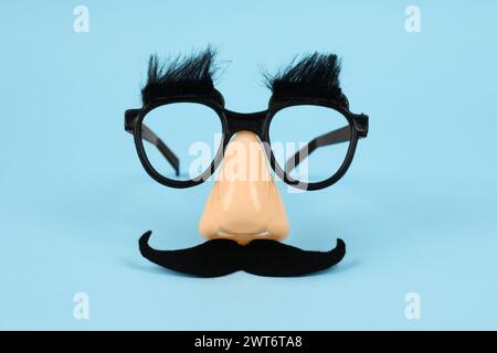 Lustige Maske mit gefälschtem Schnurrbart, Nase und Brille auf hellblauem Hintergrund Stockfoto