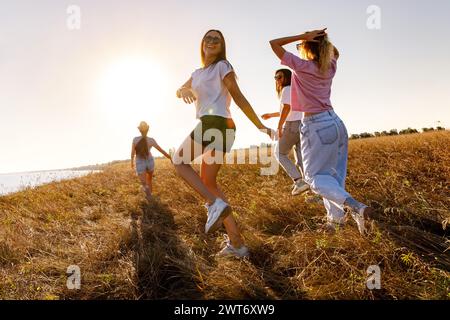 Glückliche junge Freunde haben Spaß und spazieren auf der Sonnenuntergangswiese Stockfoto