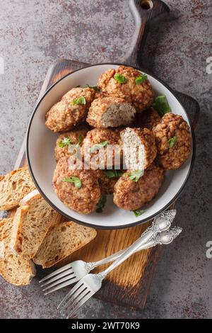 Buchweizenfleischbällchen aus Hackfleisch und gekochtem Buchweizenbrei mit Zwiebeln, Gewürzen in Nahaufnahme auf einem Teller auf dem Tisch. Vertikale Draufsicht von oben Stockfoto