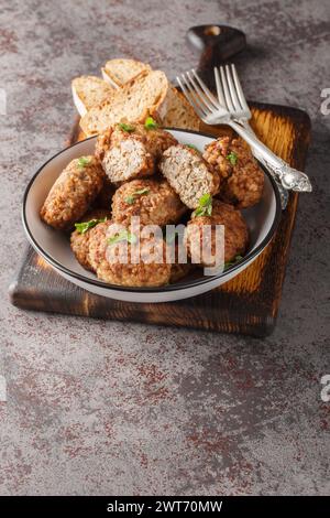 Buchweizenfleischbällchen aus Hackfleisch und gekochtem Buchweizenbrei mit Zwiebeln, Gewürzen in Nahaufnahme auf einem Teller auf dem Tisch. Vertikal Stockfoto