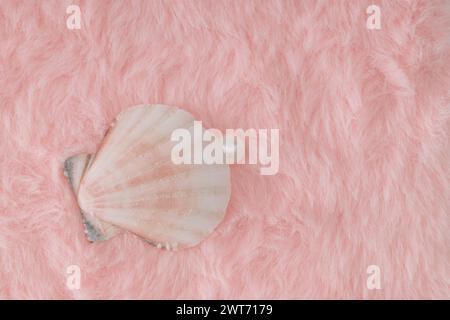 Kreative Nahaufnahme-Komposition aus Muschel und weißer Perle auf pastellrosa Kunstfellhintergrund. Minimales Retro-ästhetisches romantisches Konzept. Stockfoto