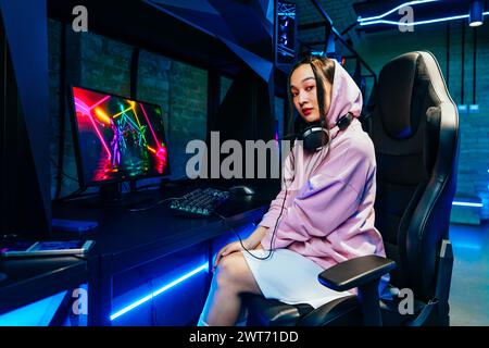 Schöne junge asiatische Frau, die Videospiele in einem Internetcafe spielt - VideoGamer, der Spaß beim E-Sport an der Computervideospielkonsole hat Stockfoto