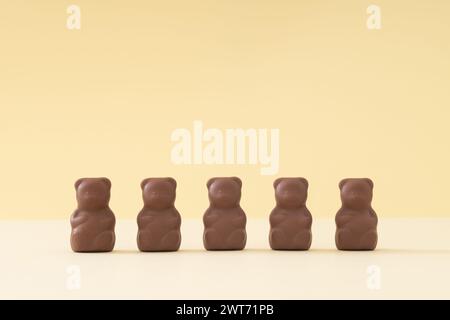 Kreatives Arrangement mit Schokoladen-Teddybären auf Pastellcremehintergrund. Kreatives Konzept für süße Speisen. Leckere Schokoladen-Teddybären-Idee. Stockfoto