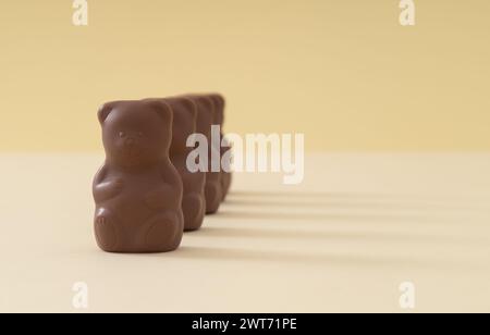 Kreatives Arrangement mit Schokoladen-Teddybären auf Pastellcremehintergrund. Kreatives Konzept für süße Speisen. Leckere Schokoladen-Teddybären-Idee. Stockfoto