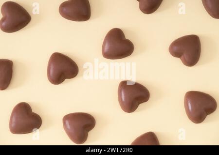 Kreatives Liebesmuster mit Schokoladenherzen auf hellbeigem Hintergrund. Minimales Liebeskonzept. Trendige Schokoladenherzen-Idee. Stockfoto