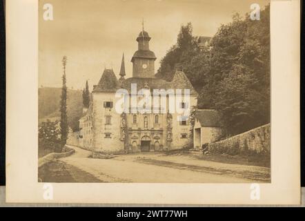 Sanctuaire Notre-Dame de Bétharram. Unbekannt, Fotograf ca. 1880er-Jahre Blick auf den Vordereingang des Sanctuaire Notre-Dame de Bétharram auf einer unbefestigten Straße. Die Steinkirche zeigt geschnitzte Statuen, eine der Jungfrau Maria und Kind über der Tür, und auf beiden Seiten, in Richtung des Eingangs. Auf den geschnitzten Tafeln auf der Vorderseite des Gebäudes stand „MARIA SINE LABE CONCEPTA / ADVOCATA NOSTRA“. Eine Person mit Hut sitzt an einer Steinmauer, die die Straße begrenzt, und schaut zur Kirche. Eine der Stationen vom Chemin du Calvaire ist über den Bäumen im Hintergrund zu sehen. (Verso, Mount) l Stockfoto