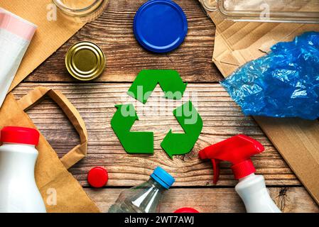 Draufsicht des Symbols des Recyclings mit verschiedenen Abfallmaterialien auf einem Holztisch. Umweltfreundliches Recyclingkonzept Stockfoto
