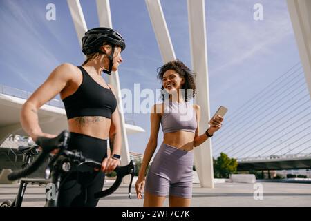 Zwei sportliche Freundinnen unterhalten sich, während sie vor dem Training in der Stadt stehen Stockfoto