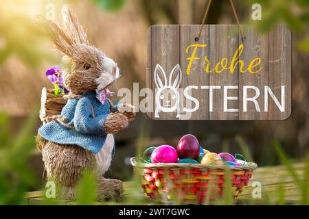 16. März 2024: Frohe Ostergrüße auf einem Schild neben einem Osterhasen mit Osternest und bunten Eiern. FOTOMONTAGE *** Frohe Ostern Grüße zum Osterfest auf einem Schild neben einem Osterhasen mit Osternest und bunten Eiern. FOTOMONTAGE Stockfoto