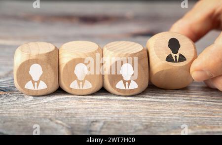 16. März 2024: Symbolisches Bild von Ausgrenzung, Rassismus und Diskriminierung. Holzwürfel mit weißen Volksfiguren und einer schwarzen Volksfigur, die eine Hand wegdreht. FOTOMONTAGE *** Symbolbild Ausgrenzung, Rassismus und Diskriminierung. Holzwürfel mit weißen Menschen Figuren und einer schwarzen Menschen Figur die eine Hand weg dreht. FOTOMONTAGE Stockfoto