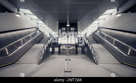 Leere Eingangshalle der U-Bahn-Station mit Treppen und Aufzug. Symmetrische Ansicht des Eingangs zum erhöhten Bahnhof. Innenraum in Grautönen. Stockfoto