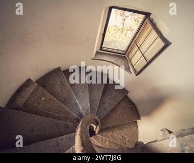 Alte Steintreppe in einem Turm - Blick von oben auf die Treppe. Perspektivische Sicht nach unten auf die runde Treppe im Uhrzeigersinn. Stockfoto