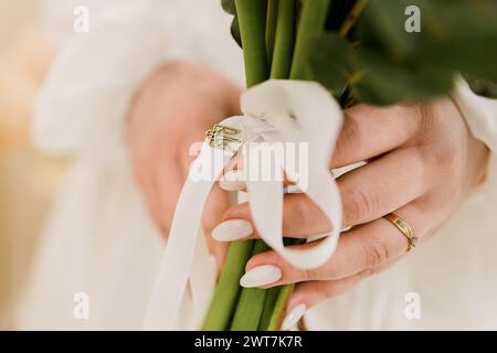 Die Braut hält einen Hochzeitsstrauß mit einem Bräutigam in den Händen Stockfoto