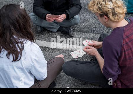 Regensburg, Deutschland. März 2024. Demonstranten blockieren die Kreuzung Kumpfmühler Str. und Fritz-Fend-Straße und spielen auf der Straße Karten. Die letzte Generation protestiert gegen die Klimapolitik der Ampelregierung. Quelle: Daniel Vogl/dpa/Alamy Live News Stockfoto