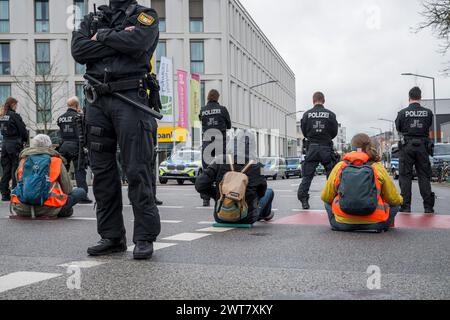 Regensburg, Deutschland. März 2024. Demonstranten, die auf der Straße sitzen, blockieren die Kreuzung Kumpfmühler Str. und Fritz-Fend-Straße. Die letzte Generation protestiert gegen die Klimapolitik der Ampelregierung. Quelle: Daniel Vogl/dpa/Alamy Live News Stockfoto