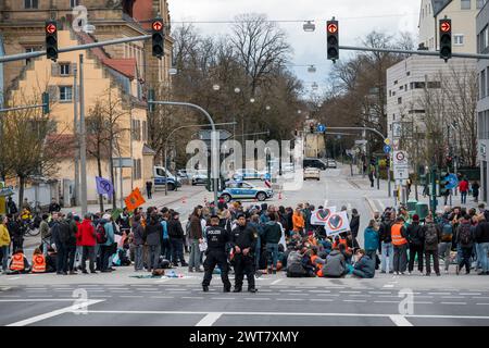 Regensburg, Deutschland. März 2024. Demonstranten stehen und sitzen auf der Straßenblockade die Kreuzung Kumpfmühler Str. und Fritz-Fend-Straße. Die letzte Generation protestiert gegen die Klimapolitik der Ampelregierung. Quelle: Daniel Vogl/dpa/Alamy Live News Stockfoto