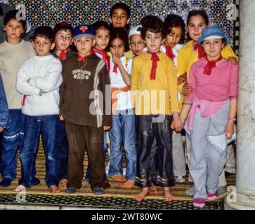 Meknes, Marokko. Schulkinder besuchen das Mausoleum von Moulay Ismail. Sie haben ihre Schuhe ausgezogen, weil sie in einer Moschee sind. Stockfoto
