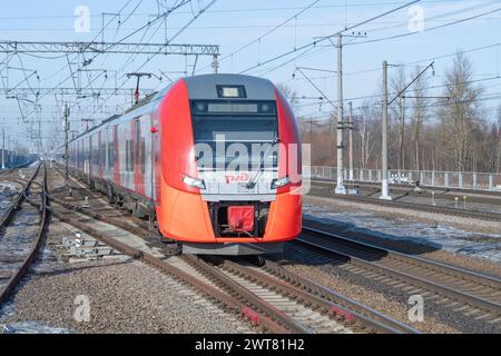 PETRO-SLAVJANKA, RUSSLAND - 4. MÄRZ 2024: Elektrozug ES2G-144 'Lastochka' kommt an einem sonnigen Märztag auf dem Bahnhof Slavjanka an. Oktyabrskaja Rail Stockfoto