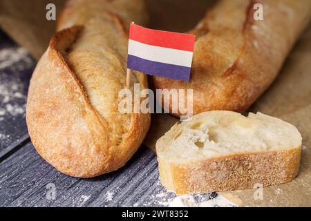 Augsburg, Bayern, Deutschland - 16. März 2024: Frisches französisches Baguette-Brot mit französischer Flagge. Symbolisches Bild von Brot und Baguette aus Frankreich *** frisches französisches Baguette Brot mit einer Frankreich Fahne. Symbolbild Brot und Baguette aus Frankreich Stockfoto