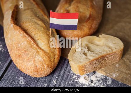 Augsburg, Bayern, Deutschland - 16. März 2024: Frisches französisches Baguette-Brot mit französischer Flagge. Symbolisches Bild von Brot und Baguette aus Frankreich *** frisches französisches Baguette Brot mit einer Frankreich Fahne. Symbolbild Brot und Baguette aus Frankreich Stockfoto