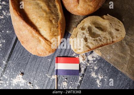 Augsburg, Bayern, Deutschland - 16. März 2024: Frisches französisches Baguette-Brot mit französischer Flagge. Symbolisches Bild von Brot und Baguette aus Frankreich *** frisches französisches Baguette Brot mit einer Frankreich Fahne. Symbolbild Brot und Baguette aus Frankreich Stockfoto