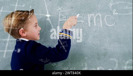 Bild von Mathe-Formeln über dem kaukasischen Jungen, der auf Tafel schreibt Stockfoto