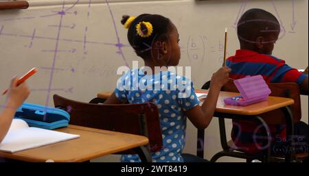 Bild von Mathe-Formeln über afroamerikanische Kinder, die in der Schule lernen Stockfoto