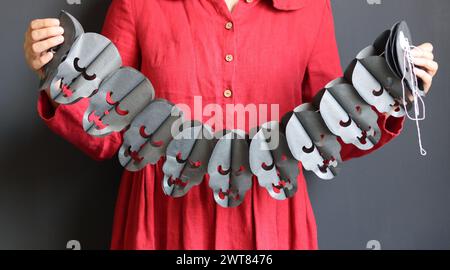 Halloween-Vorbereitungen. Junge Frau mit festlicher Girlande auf schwarzem Hintergrund mit Kopierraum. Halloween-Dekorationen aus nächster Nähe Foto. Stockfoto